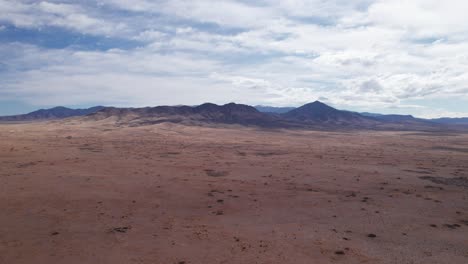 Disparo-De-Dron-Aumentando-La-Elevación-Sobre-Un-Desierto,-Con-Vistas-A-Una-Cordillera