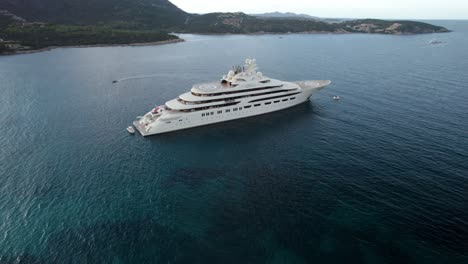 Aerial-cinematic-orbit-over-the-Dilbar,-a-third-biggest-private-luxury-yacht-belongs-to-the-Russian-billionaire-Alisher-Usmanov-anchoring-on-the-emerald-waters-near-Porto-Cervo-in-Sardinia