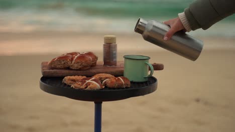 Breakfast-on-the-beach-with-delicious-sweet-breads-and-coffee,-luxury-picnic-lifestyle-during-relaxing-vacations