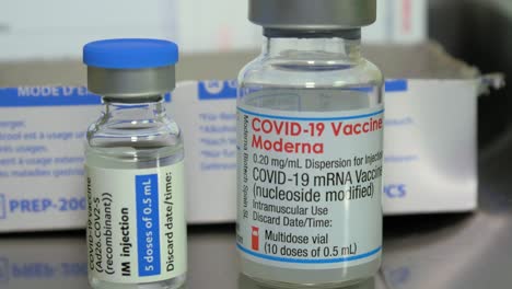 Covid-19-vaccine-jars-and-a-disposable-plastic-syringe,-medical-preparations-in-background
