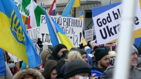 Close-up-of-protesters-in-a-pro-Ukraine-event-who-demonstrate-against-war-with-Russia-with-Ukrainian-flags-and-signs-like-"God-bless-Ukraine