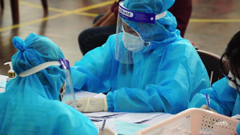 Close-up-of-personnel-seen-wearing-protective-suits-in-a-vaccination-hub
