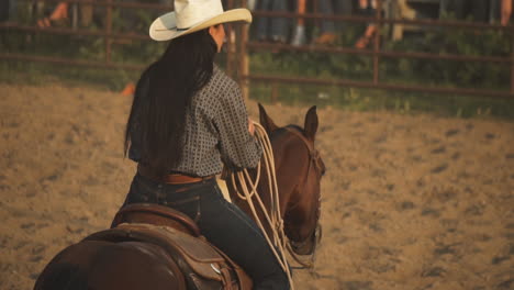 Girl-breaks-in-a-horse-Cowgirl-horseback-riding-at-sunset-in-green-field,-majestic-horse-trotting-in-slow-motion-with-rider