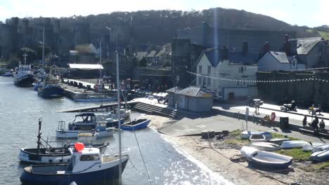 Scenic-Welsh-coastal-fishing-market-landmark-castle-town-harbour,-ships-anchored-on-river