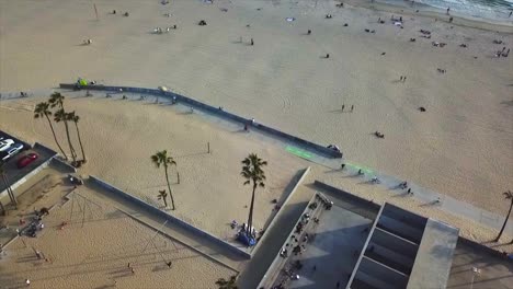 Venice-Beach,-Kalifornien,-Drohnenschuss,-Der-Sich-Vorwärts-Bewegt-Und-Am-Strand-über-Basketballplätze-Mit-Sand-Und-Wasser-Schwenkt