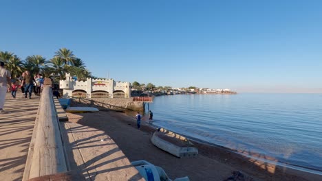 People-walking-promenade-along-Dahab-beach,-Egypt