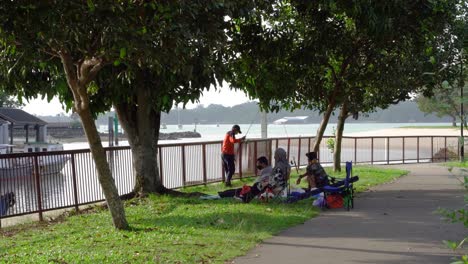 Family-fishing-and-having-a-picnic-at-Changi-Beach-Park,-Singapore