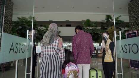 West-Java-Indonesia-10-December-2022-:-The-family-enters-the-hotel-to-check-in-and-have-a-vacation-and-is-greeted-by-the-hotel-staff
