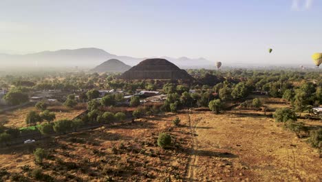 Drone-footage-over-pyramid-with-hot-air-balloon-on-the-back-at-the-morning