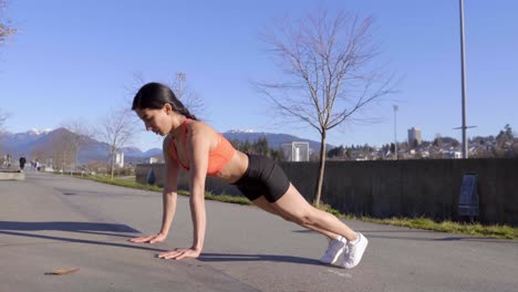 Young-woman-exercising-outdoors-elevated-pushups-Wide-shot