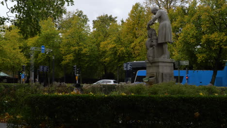Wide-shot-of-autumn-park-with-Christopher-Polhem-statue-and-traffic-on-road-in-background--Gothenburg,Sweden