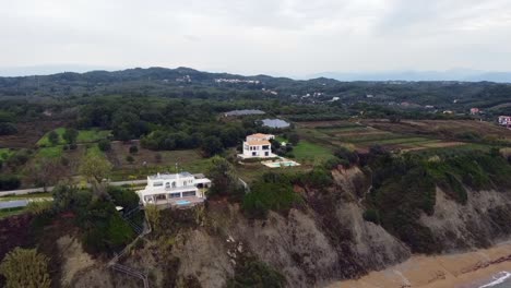 Buttery-soft-aerial-drone-flight-fly-forwards-drone-shot-from-offshore-tu-luxury-villas-on-a-cliff