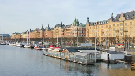 Beautiful-view-of-the-Stockholm-in-famous-Strandvagen-street,-historic-area-with-small-house-boats-floating-in-the-clean-fresh-water-on-a-bright-sunny-day-in-Sweden