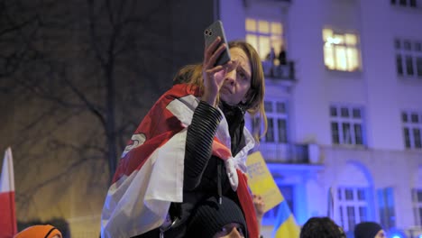 2022-Russische-Invasion-In-Der-Ukraine---Mädchen-Mit-Einer-Flagge-Des-Freien-Weißrusslands,-Das-Am-Allerersten-Kriegstag-Mit-Ihrem-Telefon-Bei-Einer-Antikriegsdemonstration-In-Warschau-Filmt