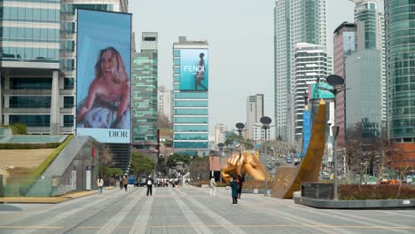 Menschen-Mit-Gesichtsmasken-Gehen-Auf-Gangnam-Straßen,-Während-Anzeigen-Von-Dior-Und-Fendi-Im-Hintergrund-Bei-Seoul-Coexstatic-Laufen