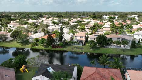 An-aerial-shot-over-a-residential-neighborhood-in-Florida-on-a-sunny-day-with-a-dark,-deep-canal