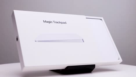 Apple-company-logo-visible-on-the-side-of-half-opened-white-package-box-of-Mac-magic-trackpad-on-display-stand