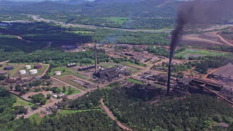 Aerial-view-of-dark-smoke-rising-from-Mine-and-plant-chimneys,-polluting-the-nature---orbit,-drone-shot