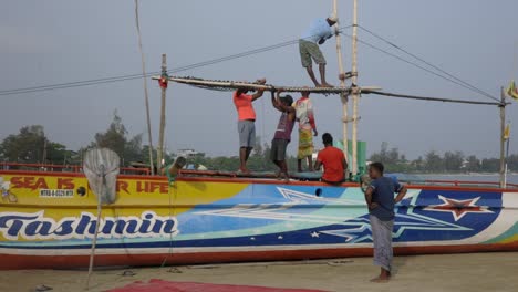 Slow-Motion-Shot-Of-Sailors-Working-As-Team-On-Colorful-Boat-At-Jungle-Sandy-Beach,-Weligama,-Sri-Lanka