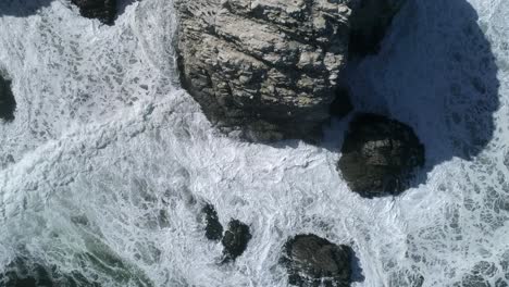 Drone-Descending-Through-Towering-Cliffs-With-Foamy-Waves-At-Piedra-de-la-Piramide-In-Linares,-Chile