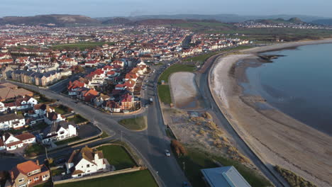 An-aerial-view-of-Llandudno-south-beach-and-shoreline-on-a-sunny-evening,-flying-towards-the-beach-from-the-Great-Orme,-Clwyd,-North-Wales,-UK