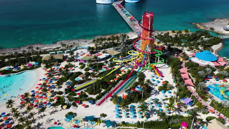 Wide-Cinematic-rising-drone-shot-of-CoCoCay-island-with-water-slides-and-a-Royal-Caribbean-cruise-ship-in-the-background,-tilting-upward