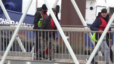 Young-migrant-men-walk-up-the-walkway-in-the-port-of-Dover,-UK
