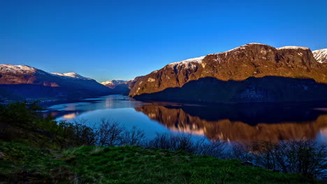 Time-lapse-shot-of-beautiful-sunrise-in-Fjord-surrounded-by-snowy-mountains-and-blue-sky---Norwegian-Fjord,Flam-in-Norway