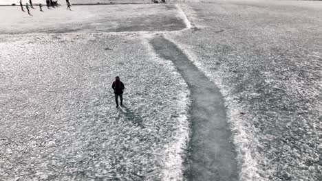 Aerial-Birds-Eye-View-Of-Lonely-Adult-Male-Walking-Across-Snow-Covered-Ground-At-Khalti-Lake