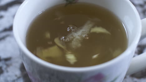 Close-Up-View-Of-Swirling-Ginger-And-Lemon-Pieces-In-Honey-Hot-Drink
