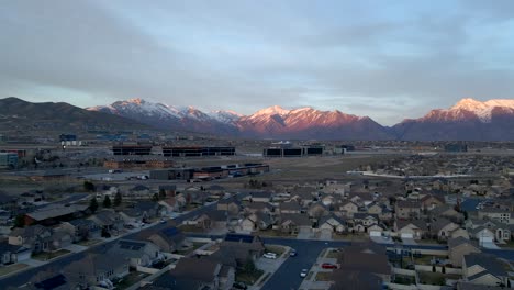 Silicon-Slopes-in-Lehi,-Utah-with-office-buildings-and-a-suburban-community-below-the-snow-capped-mountains---sliding-aerial-view