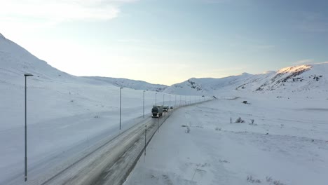 Cars-and-trucks-crossing-snow-covered-mountain-Hemsedalsfjellet-in-Norway---Sunny-clear-day-during-sunset-hours