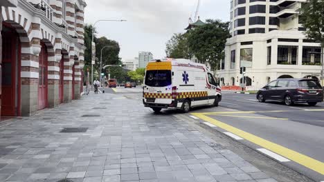 An-emergency-medical-response-vehicle-on-the-road,-driving-out-from-historical-central-fire-station-with-loud-siren-and-flashy-lights,-close-up-shot-at-Singapore-metropolitan-area