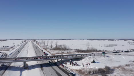 Aerial-pullback-shows-protesting-people-gathered-to-support-freedom-convoy-on-overpass-at-hwy417-near-cownall-ontario