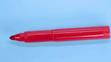 Roter-Markierungsstift,-Der-Sich-Auf-Blauem-Oberflächenhintergrund-Dreht,-Makroaufnahme-Nahaufnahme-Detail