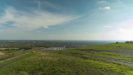 Small-industrial-townscape-with-wind-turbines-from-mining-heap-on-vibrant-sunny-day,-static-time-lapse-view