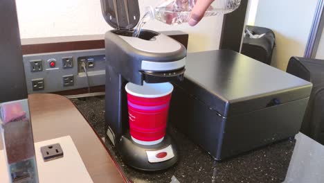 Mann-Gießt-Wasser-In-Die-Kaffeemaschine-Und-Schaltet-Sie-Ein,-Um-Morgens-Einen-Kaffee-Zum-Frühstück-Zuzubereiten-Videohintergrund-In-4k-|-Kaffeezubereitung-In-Der-Kaffeemaschine