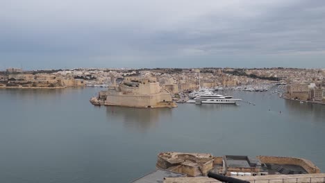 Panning-with-cityscape-of-Valletta-city,-harbour-and-luxury-yachts-in-Malta-from-Upper-Barrakka-Gardens-fort