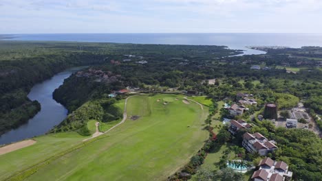 Aerial-drone-landscape-view-of-a-golf-course-and-luxury-resort-near-a-river,-Dominican-Republic