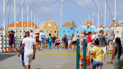 Pedestrians-and-tourists-crossing-over-the-Queen-Emma-Bridge-in-Saint-Anna-Bay-in-Willemstad,-Caribbean