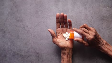 Senior-man-taking-his-medication-pills,-unrecognizable-old-man,-top-down-shot-with-copy-space-of-an-elderly-male