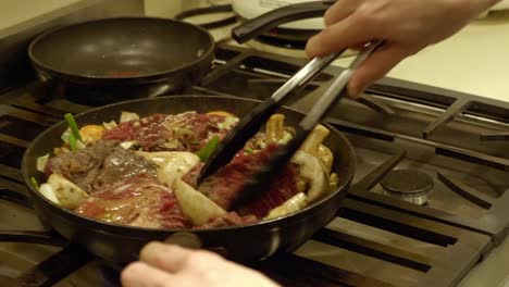 Cooking-A-Korean-Meal-With-Meat-And-Different-Ingredients-Being-Tossed-Over-Pan