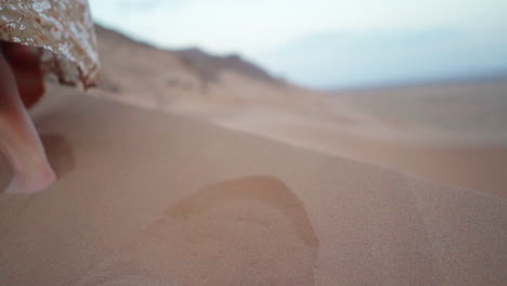 Slow-motion-feet-close-up:-Woman-in-dress-walks-on-desert-sand-dune