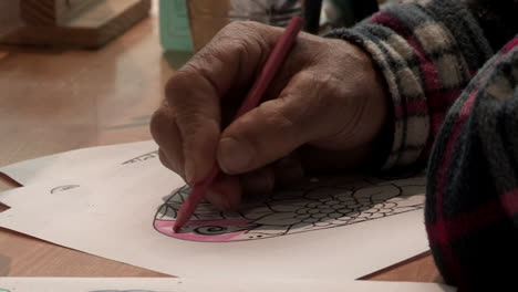 Close-up-of-a-man's-hand,-painting-a-drawing,-with-pink-pencil