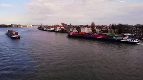 Aerial-Over-Oude-Maas-View-Of-Salute-Cargo-Ship-Going-Past-Another-Cargo-Ship-In-Dordrecht