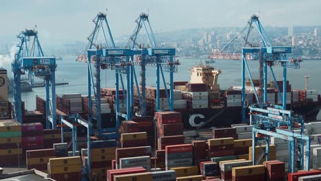 Container-Stapeln-Sich-In-Der-Nähe-Von-Kränen,-Die-Darauf-Warten,-Auf-Ein-Frachtschiff-Geladen-Zu-Werden,-Das-Im-Seehafen-Von-Valparaiso,-Chile,-Angedockt-Ist