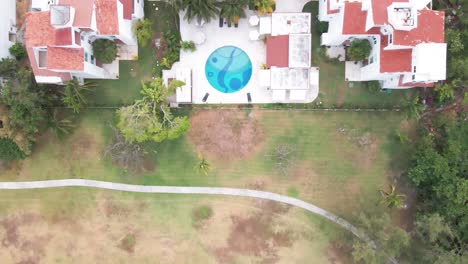Top-drone-shot-of-swimming-pool,-hotel,-houses-in-Cancun,-Mexico