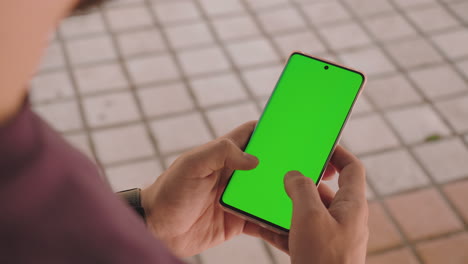 10-bit-shot-with-hands-of-a-man-writing-texting-on-a-smartphone-with-green-screen-in-the-day-time