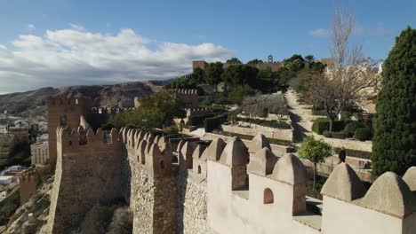 Aerial-Dolly-Left-Over-Walled-Fortification-Of-Alcazaba-of-Almería-With-Gardens-In-Background
