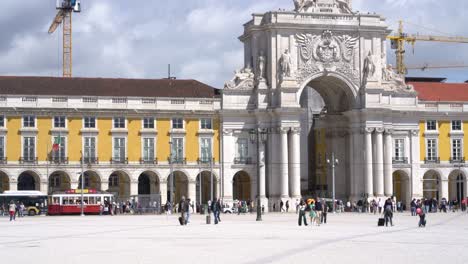 People-walking-by-the-Arco-da-Rua-Augusta-,-landmark-ornate-triumphal-arch-in-Lisbon-PraÃ§a-do-ComÃ©rcio